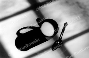 Black-and-white abstract minimalist photograph featuring shadows of a coffee mug and spoon, and window muntins.