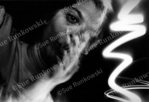 Black-and-white abstract photo with a blurred human face and lightning-like light streaks conveying motion and energy.