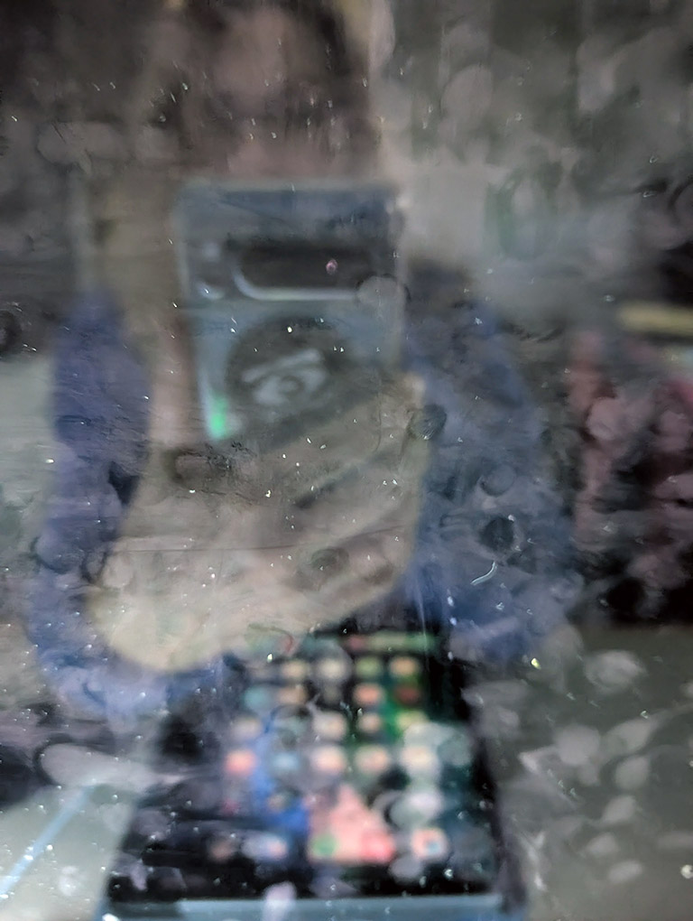 image of woman holding a cell phone taking a photo in the reflection of a computer monitor