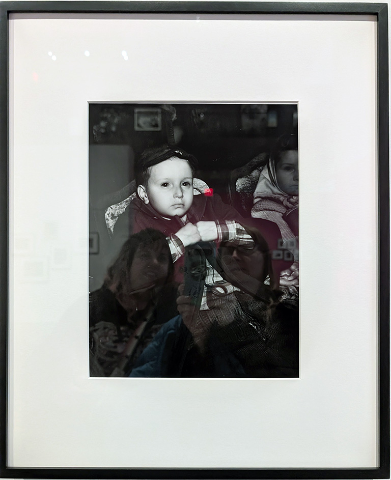 Black and white documentary photograph of young boy in a movie theater, emotional fine art portrait capturing childhood, classic social realism image.