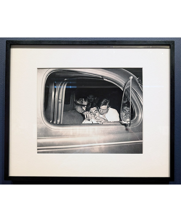 Vintage black and white street photograph capturing an intense candid moment inside a car after a car crash, mid-century urban life, iconic noir-style photography.