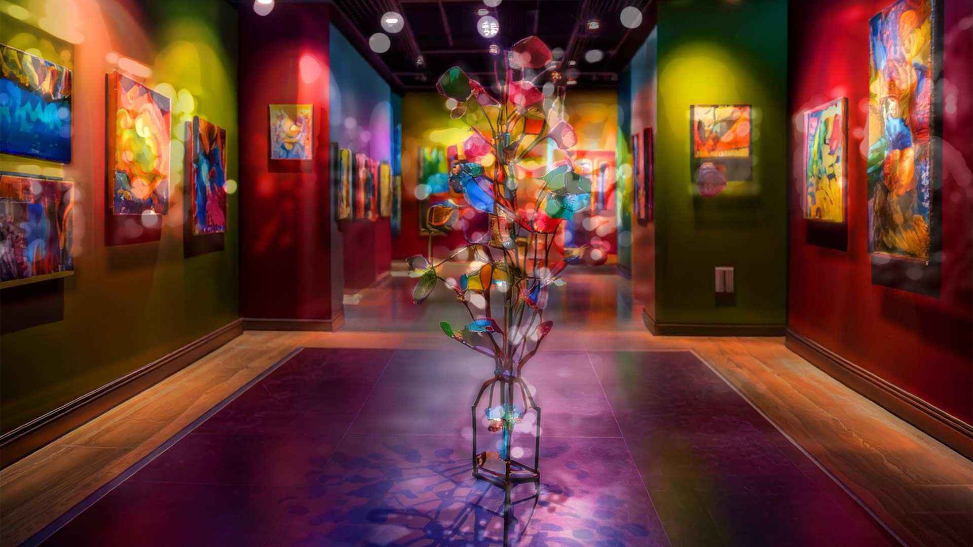A brightly lit art gallery with colorful walls displaying abstract paintings, centered on a whimsical sculptural installation resembling a glowing tree made of multicolored glass or lights, with soft, floating light reflections throughout the space.